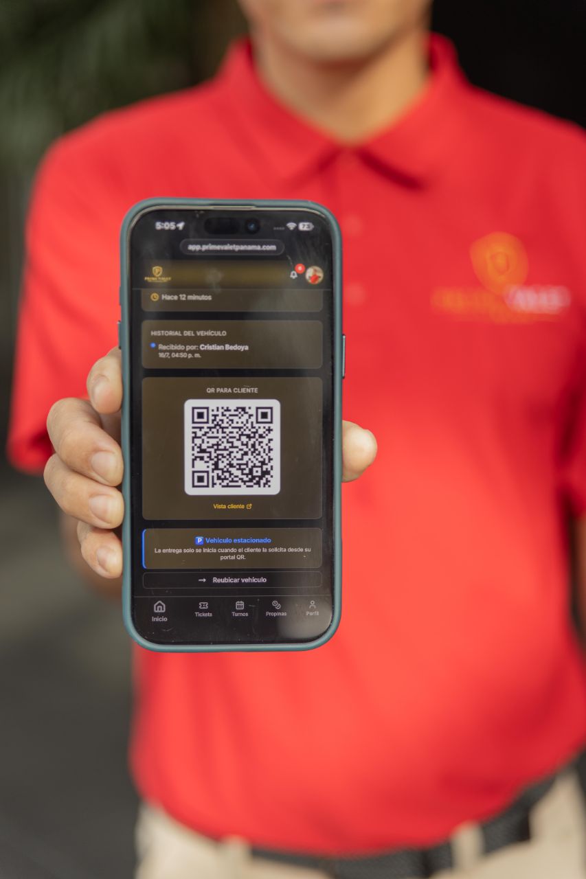 Valet de Prime Valet sostiene su teléfono mostrando el código QR y el historial del vehículo en la app.